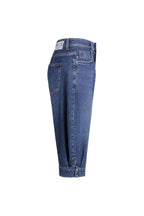Seitenansicht einer mittelblauen Jeans-Bermuda mit weißem Label-Patch am Bund und Knopfdetail am Saum.