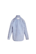 Hellblaue Denim-Bluse in der Rückansicht mit weißem Logo-Patch im Nackenbereich.