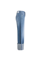 Seitenansicht einer mittelblauen Jeans mit weitem Bein, breitem Aufschlag und weißem Label-Patch am Bund.