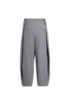 Rückansicht einer weiten grauen Hose mit markanten Seitenfalten und weißem Label-Patch.