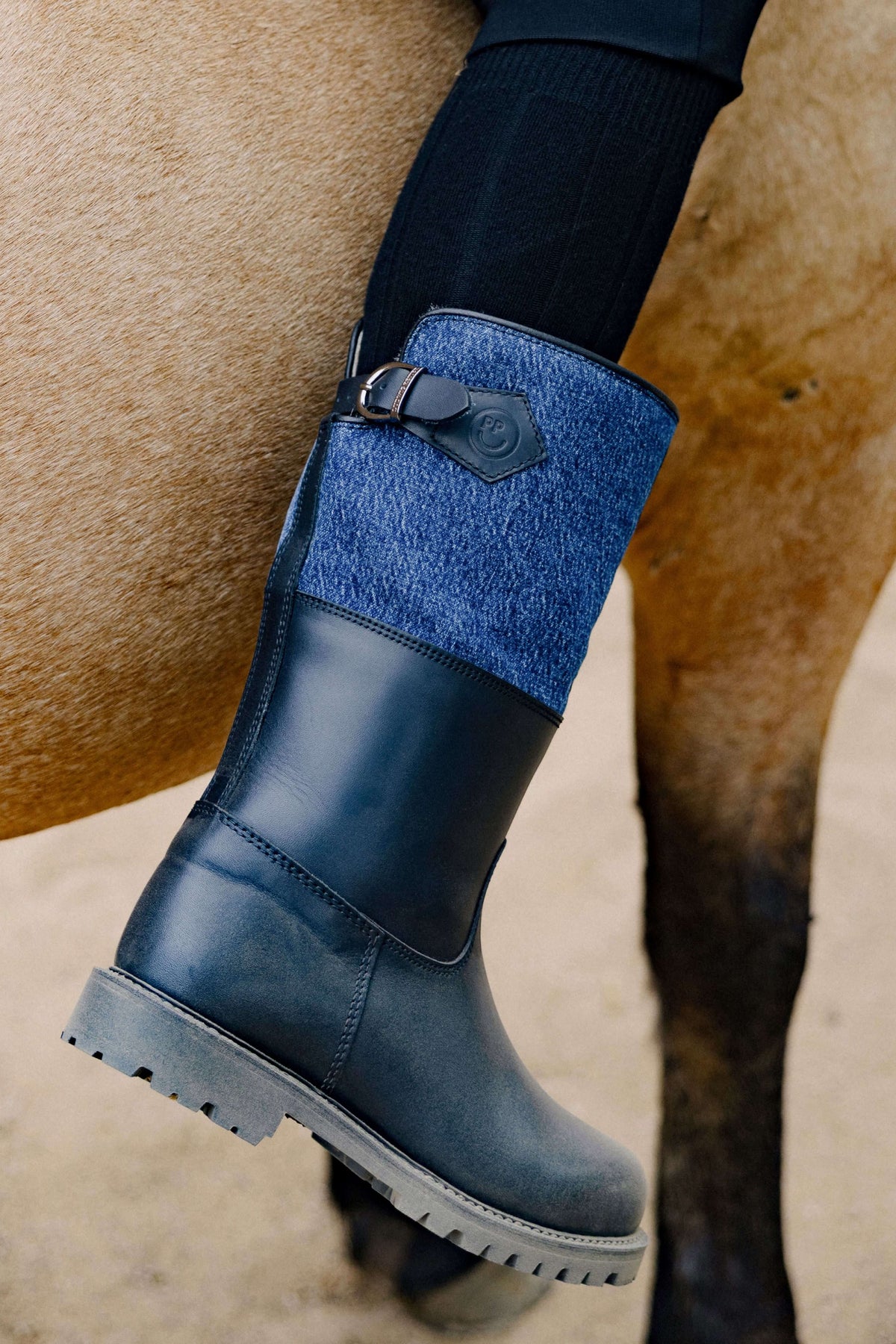 Detailansicht: Dunkelblauer Leder-Outdoor-Stiefel mit blau meliertem Filzschaft, Schnallendetail und profilierter Sohle.