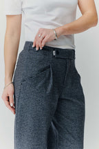 Detailansicht einer grau-blau gemusterten Hose mit feinem Muster und Logo-Detail am Bund.