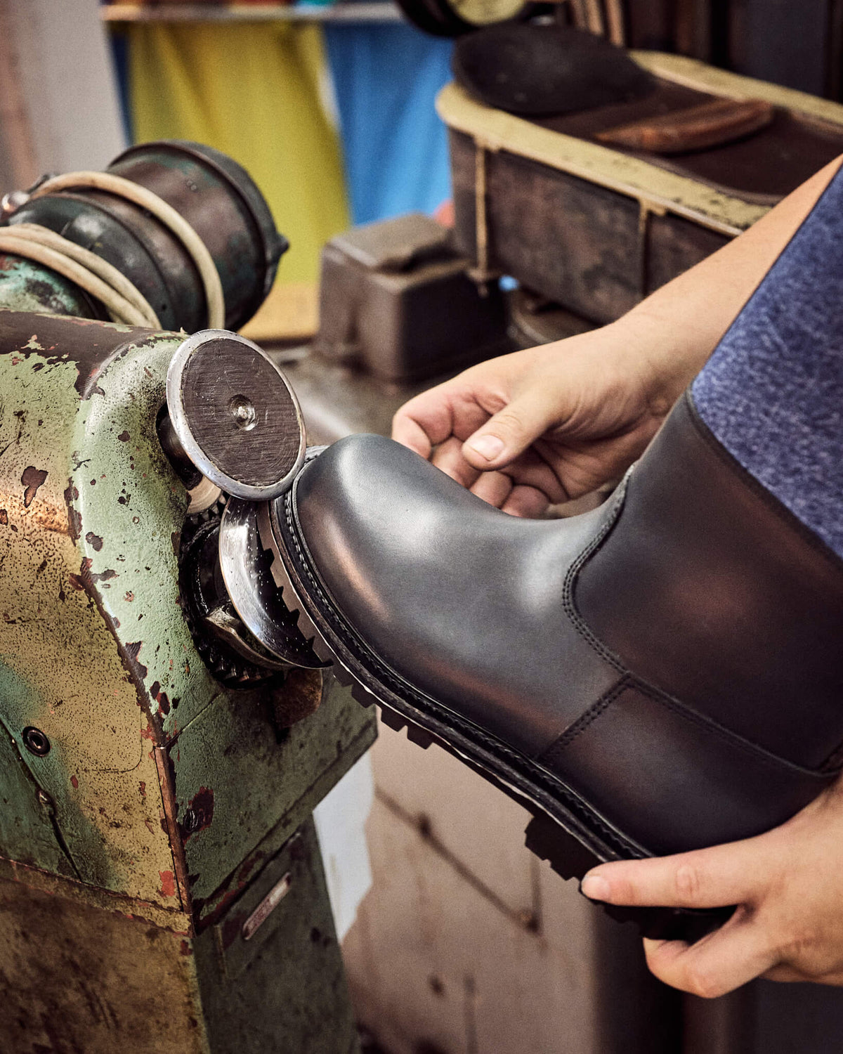 Traditionelles Schuhmacherhandwerk: Der Sohlenrand des Lederstiefels wird an einer mechanischen Schleifmaschine präzise in Form gebracht und poliert.