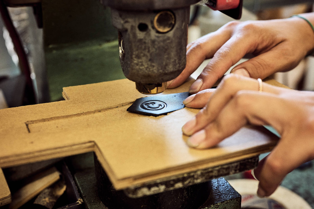 Präzise Handarbeit: Das Markenlogo wird mit einer Heißprägemaschine in das kleine Leder-Patch für den Stiefelschaft geprägt.