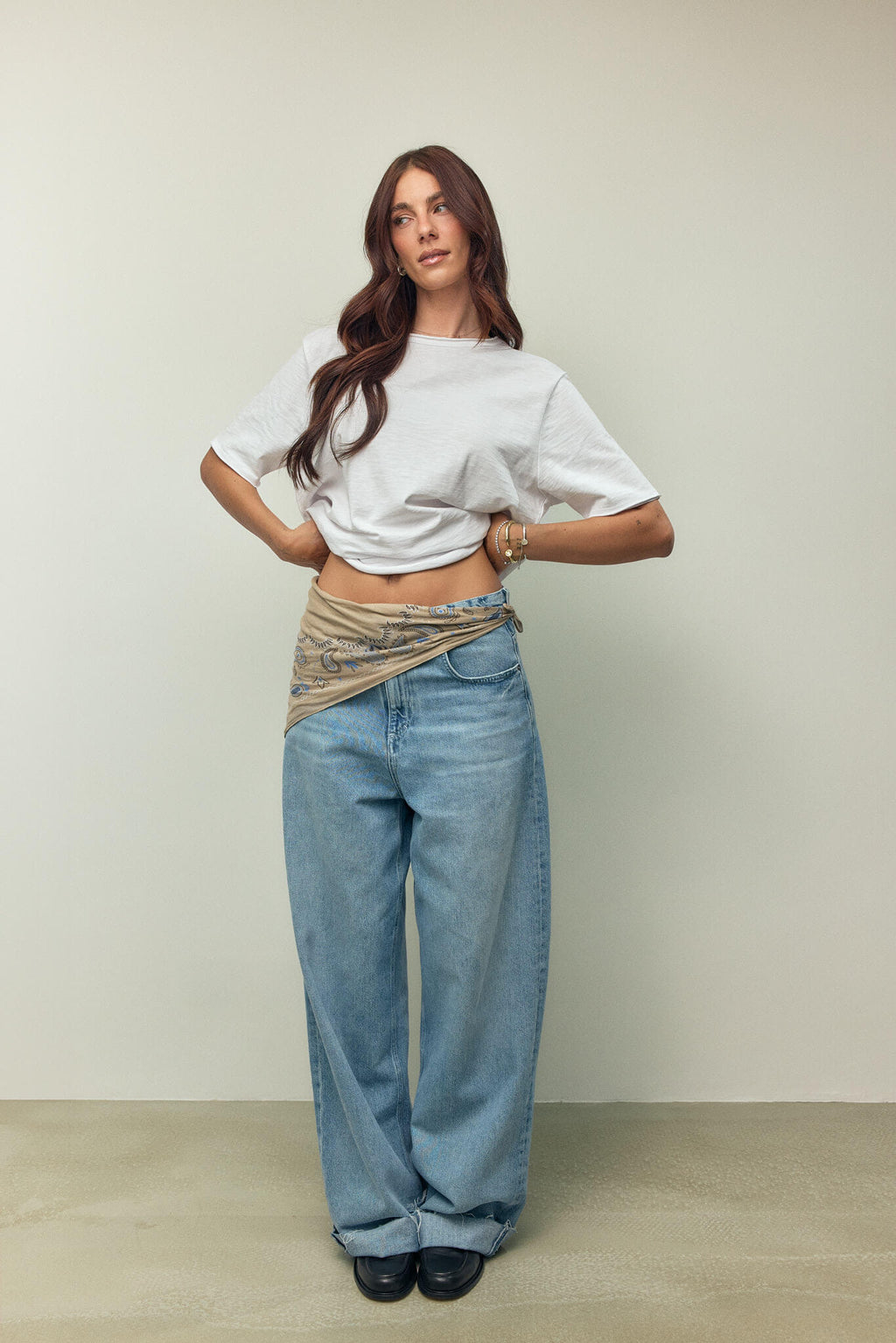 Frau in weißem T-Shirt und weiter hellblauer Jeans mit einem beigen Paisley-Bandana als Gürtel-Detail.