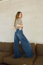 Eine Frau steht auf einem Sofa. Man sieht die Jeans von hinten, mit einem sehr weiten Bein 32_THE HIP HOP in dunkelblau.