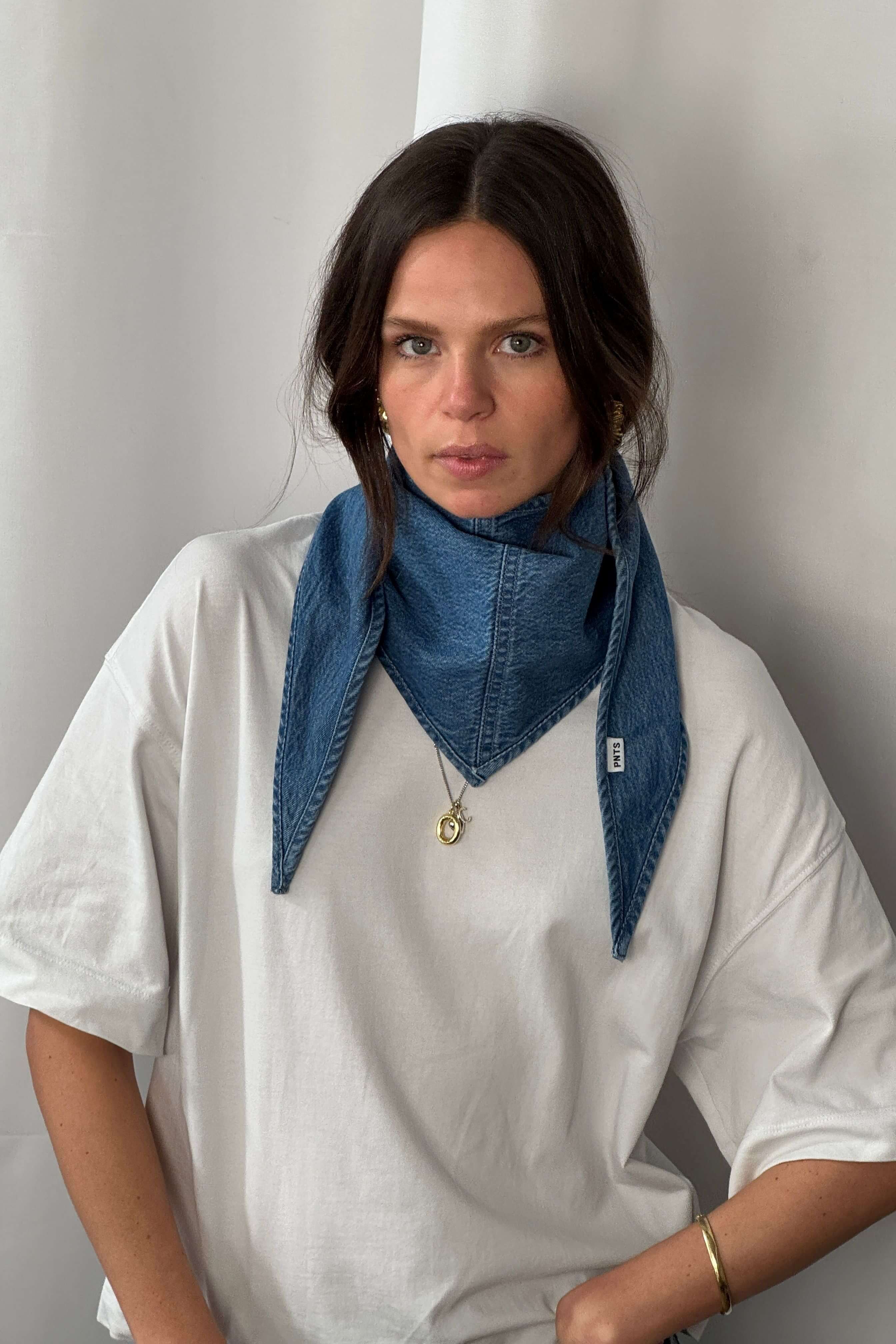 Frau in weißem Oversized-T-Shirt trägt ein blaues Denim-Bandana mit PNTS-Label als Halstuch.