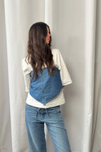 Frau trägt ein blaues Denim-Bandana als Top über einem weißen T-Shirt, kombiniert mit einer hellblauen Jeans.